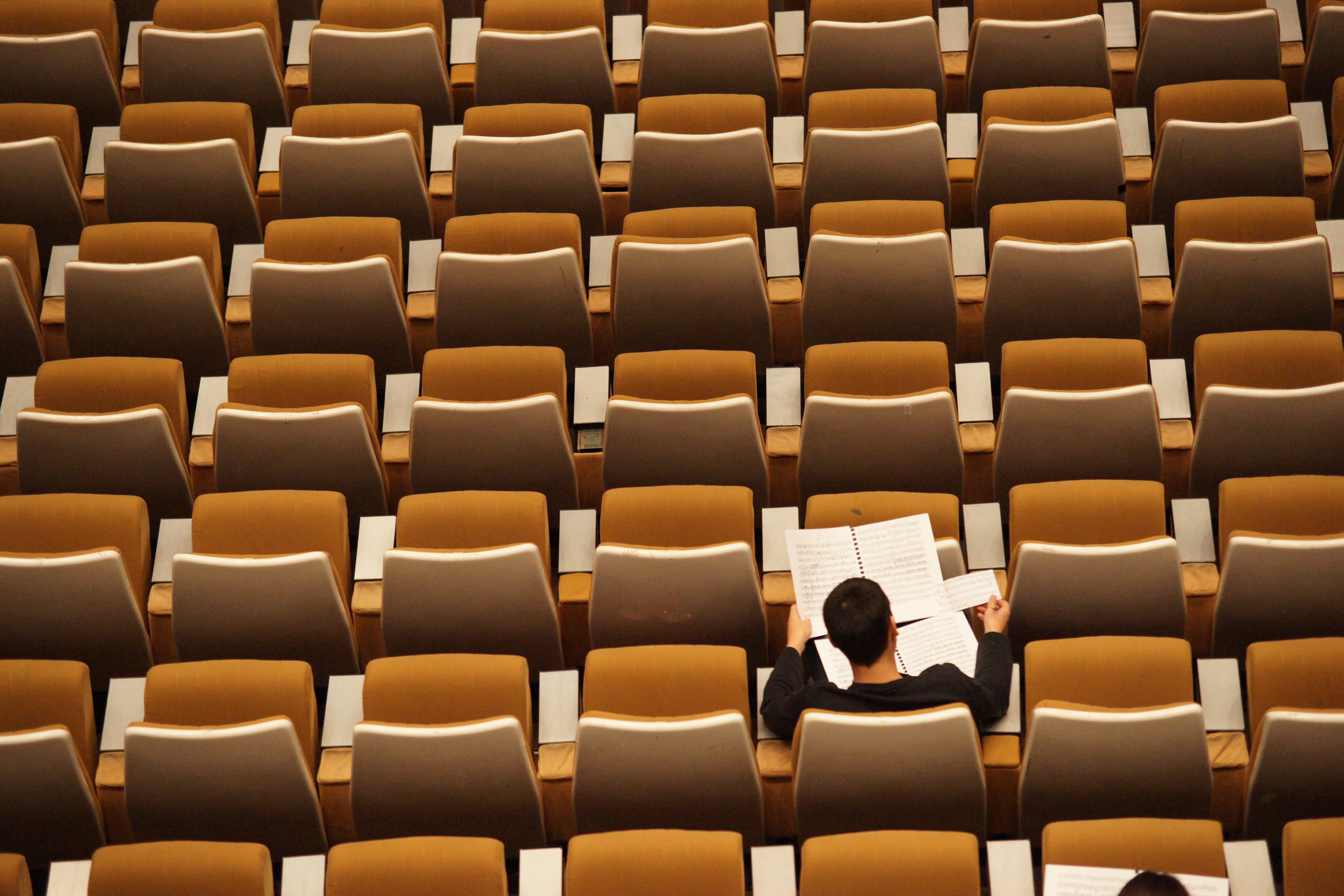 Student sitting in empty lecture hall with notes